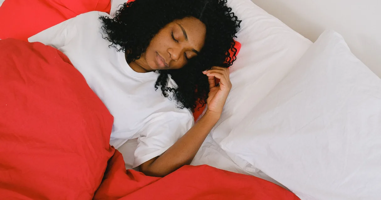 Mulher dormindo de lado na cama, com a cabeça apoiada no travesseiro